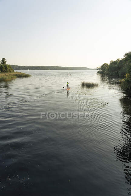 Jovem paddleboarding no lago — Fotografia de Stock
