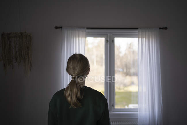 Teenage girl standing by window — Photo de stock