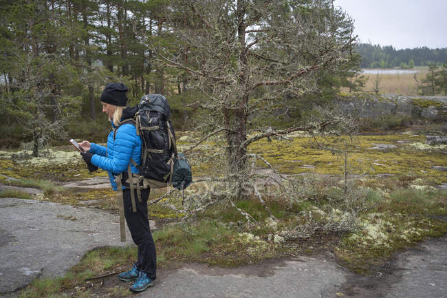 Woman using smart phone while hiking — Stock Photo