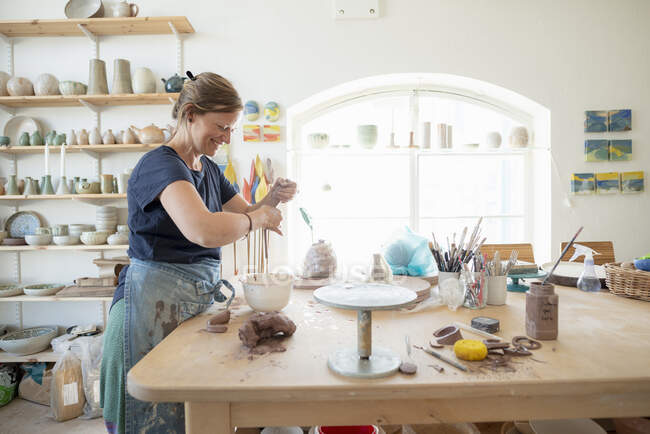Potter sosteniendo arcilla en la mesa en el taller - foto de stock