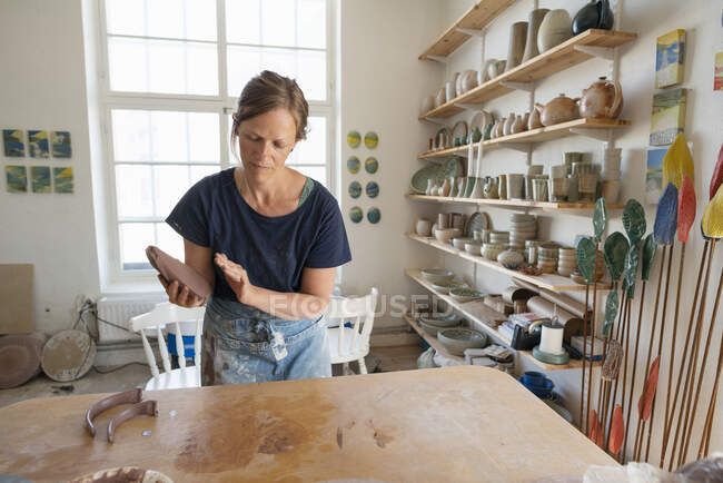 Гончар держит глину за столом в мастерской — стоковое фото