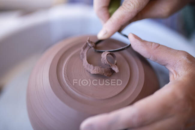 Hands of potter using scraping tool — Stock Photo