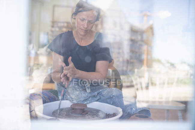 View through window of potter using pottery wheel — Stockfoto