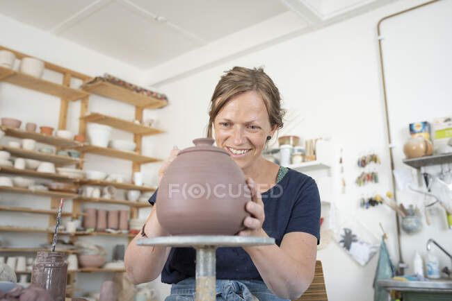 Potter making teapot in workshop - foto de stock