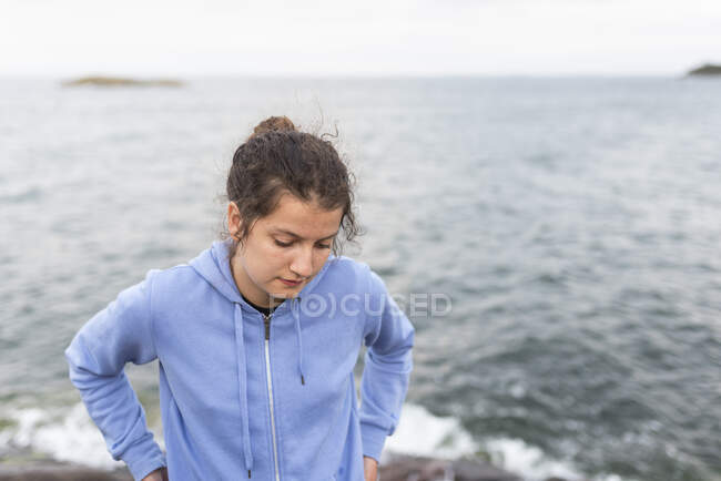 Teenage girl in hoodie by sea — Fotografia de Stock