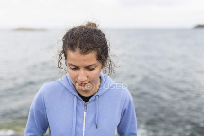 Teenage girl in hoodie by sea — Fotografia de Stock