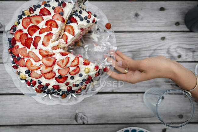Woman's hand holding plate with berry cake — Stock Photo