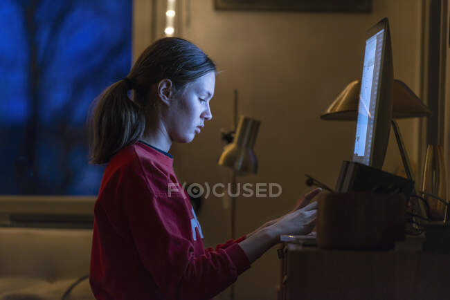Дівчина-підліток використовує комп'ютер вночі — стокове фото