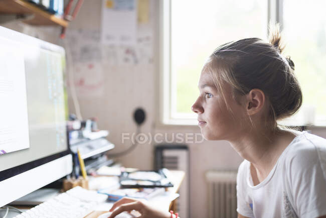 Adolescente chica haciendo la tarea en la computadora - foto de stock