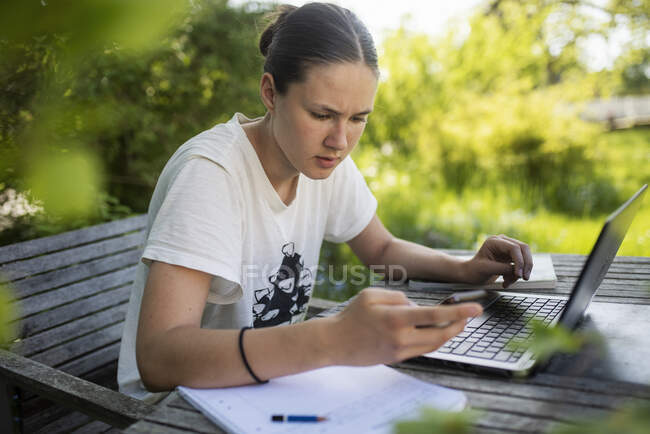 Teenage girl text messaging at outdoor table — Stock Photo
