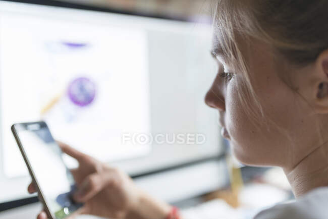 Teenage girl text messaging with smartphone at desk — Stockfoto