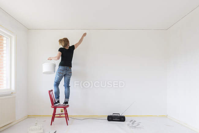 Mulher parede de pintura em casa — Fotografia de Stock