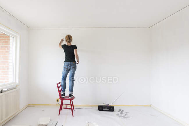 Frau bemalt Wand im Haus — Stockfoto