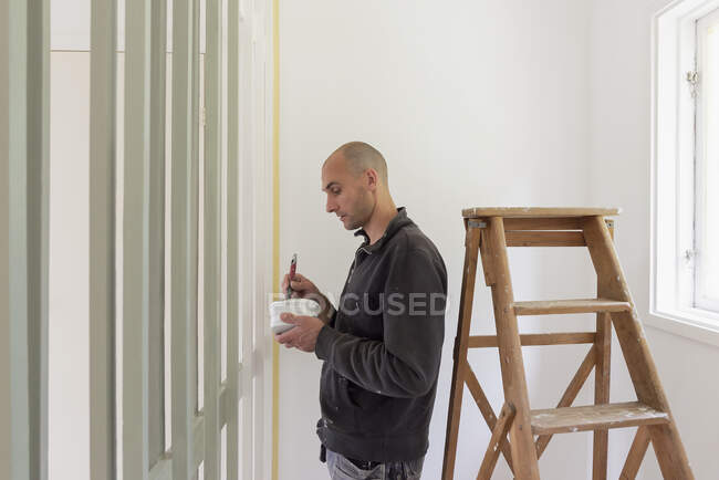 Человек рисует стены в доме — стоковое фото