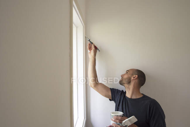 Человек рисует стены в доме — стоковое фото