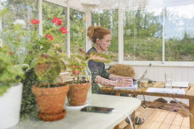 Женщина работает из дома в солнечной комнате — стоковое фото