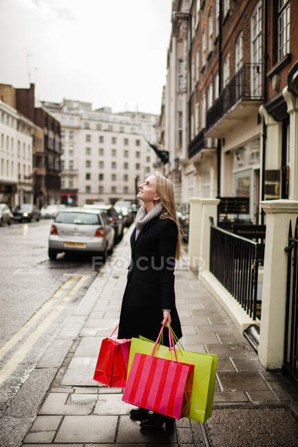 Молода жінка тримає сумочки на тротуарі. — стокове фото