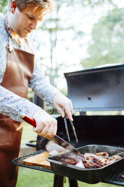 Young man cooking meat on barbecue — Stock Photo