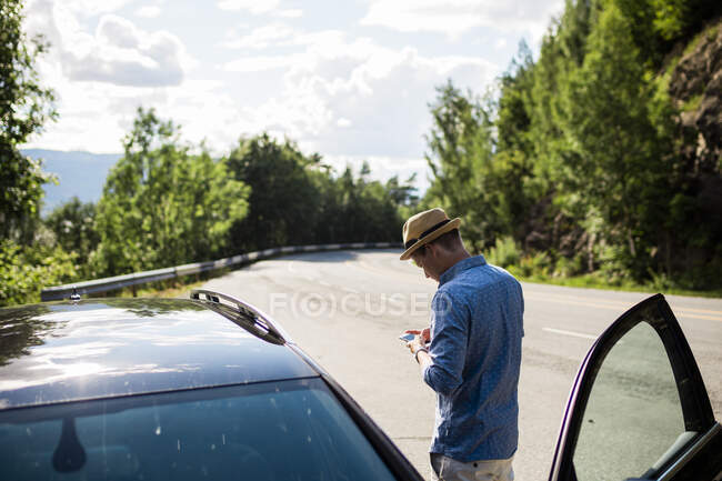 Чоловік використовує смартфон на машині на шосе — стокове фото