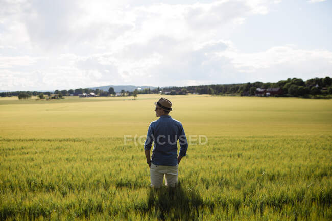 Young man in hat standing in field — Foto stock