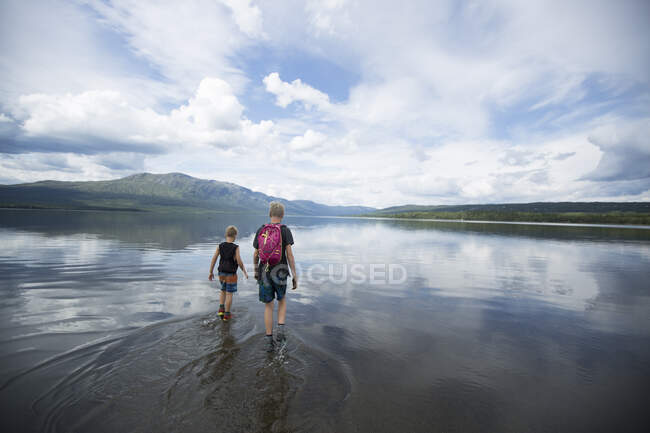 Brother wading across Ottsjo Lake in Valadalen Nature Reserve, Sweden — Fotografia de Stock