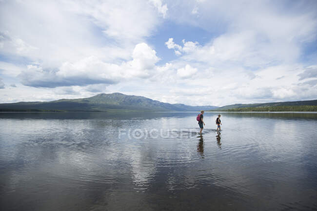 Brother wading across Ottsjo Lake in Valadalen Nature Reserve, Sweden - foto de stock
