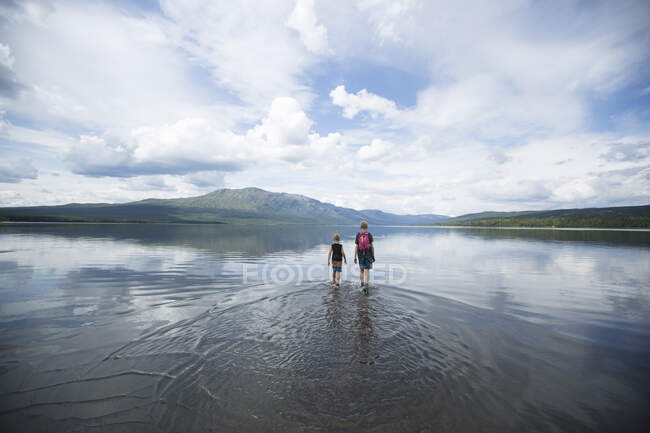 Brother wading across Ottsjo Lake in Valadalen Nature Reserve, Sweden — Fotografia de Stock