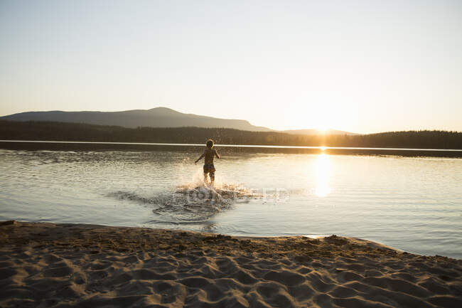 Boy splashing in Ottsjo Lake at sunset in Valadalen Nature Reserve, Sweden — Stock Photo