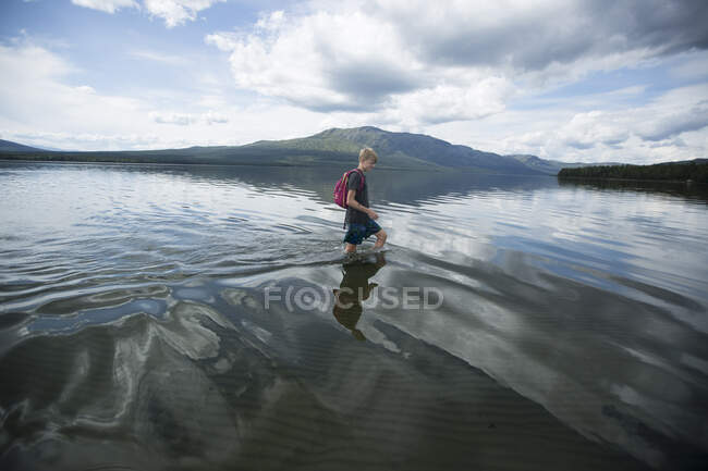 Boy wading across Ottsjo Lake in Valadalen Nature Reserve, Sweden — Stockfoto