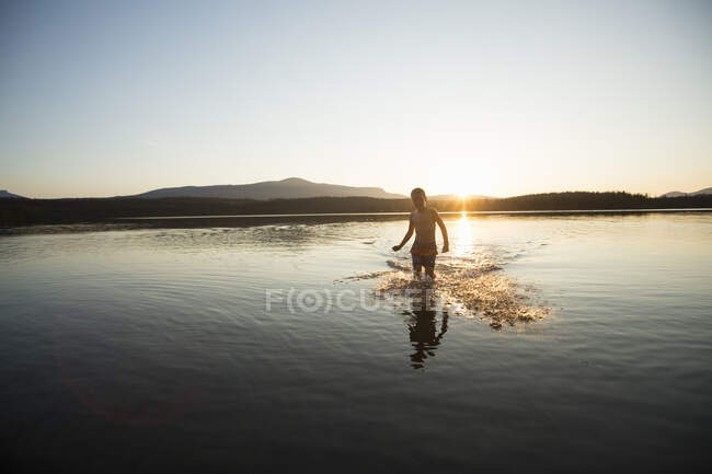 Boy splashing in Ottsjo Lake at sunset in Valadalen Nature Reserve, Sweden - foto de stock