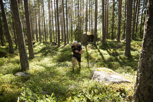 Mature man jogging on trail through forest — Photo de stock
