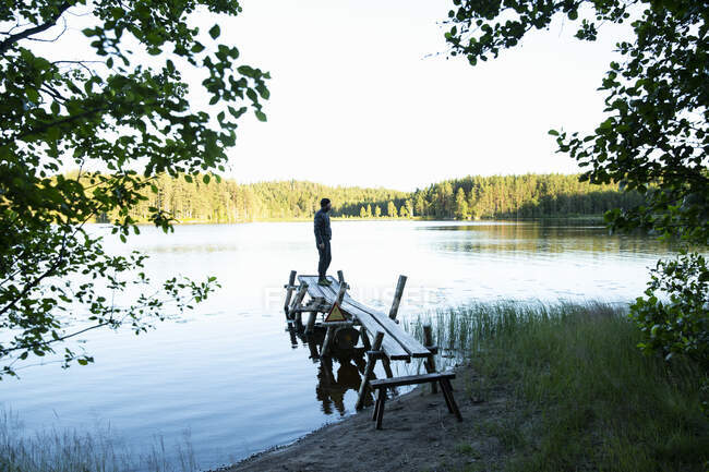 Uomo maturo in piedi sul molo nel lago — Foto stock