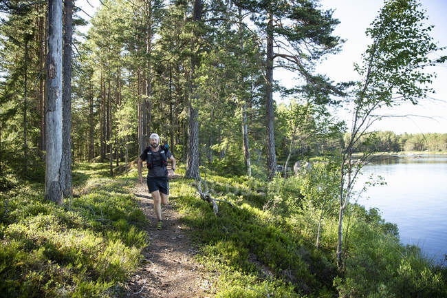 Mature man jogging on trail through forest — Fotografia de Stock