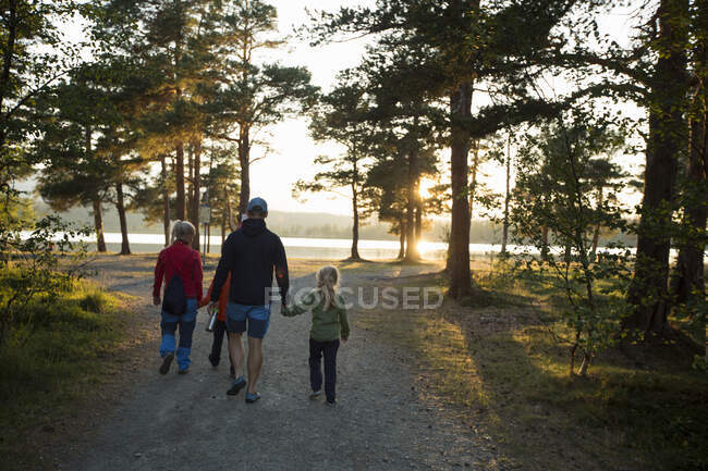 Family walking on rural road at sunset — Stockfoto