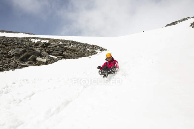 Frau rutscht im Schnee den Berg hinunter — Stockfoto