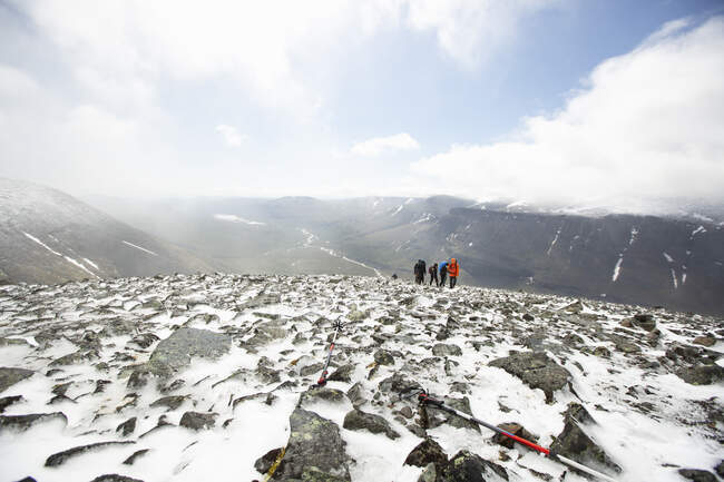 Persone che camminano tra neve e rocce in montagna — Foto stock