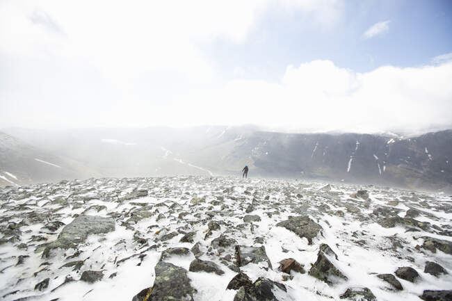 Hombre de senderismo en la montaña con rocas y nieve - foto de stock
