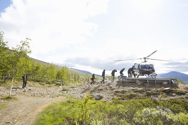 Personas abordando helicóptero en la montaña - foto de stock