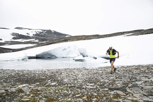 Hombre maduro corriendo por el lago en la montaña - foto de stock