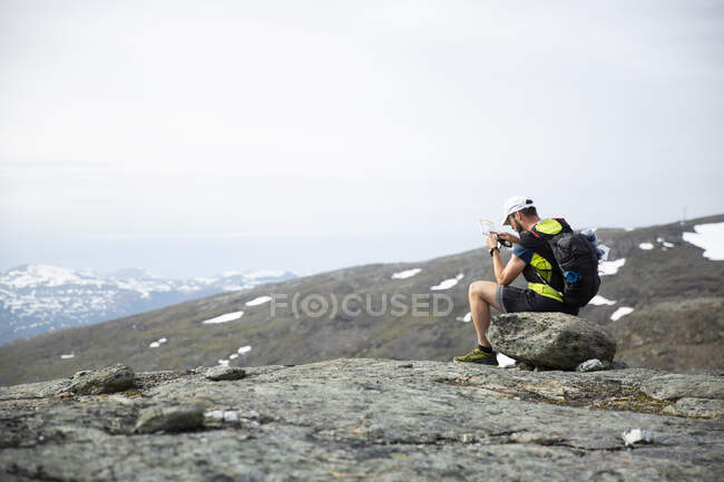 Зрелый человек смотрит на карту и компас на горе — стоковое фото