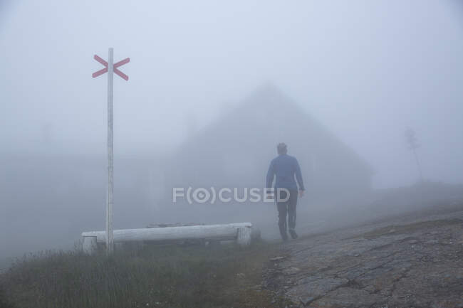 Uomo maturo a piedi fino alla cabina nella nebbia — Foto stock