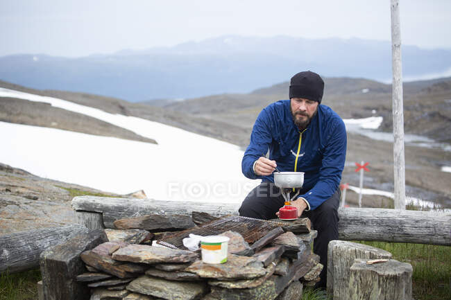 Mature homme cuisine sur la montagne — Photo de stock
