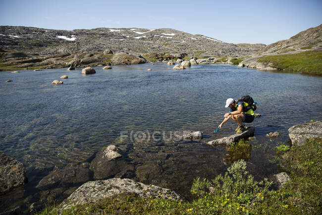 Mature man drinking water from lake — Fotografia de Stock
