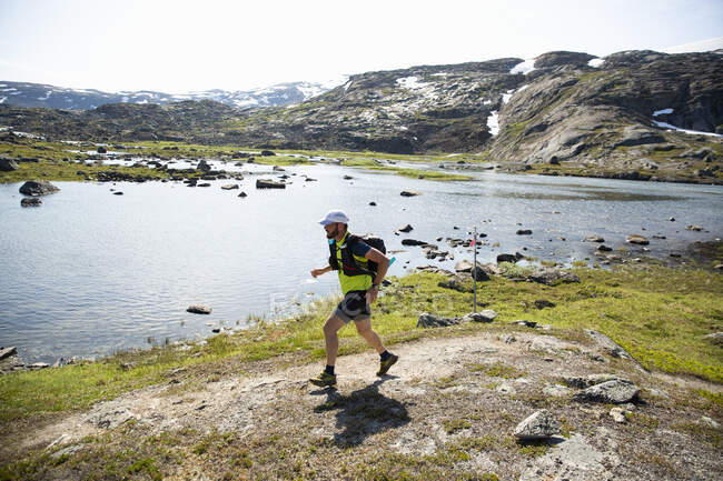 Mature man jogging by lake — Foto stock