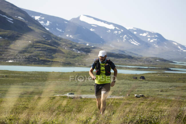 Mature man jogging by mountain — Stockfoto