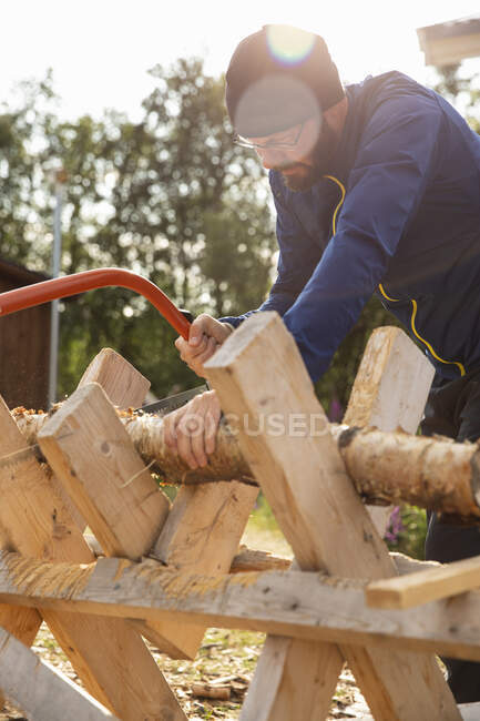 Man cutting firewood at sunset — Stock Photo