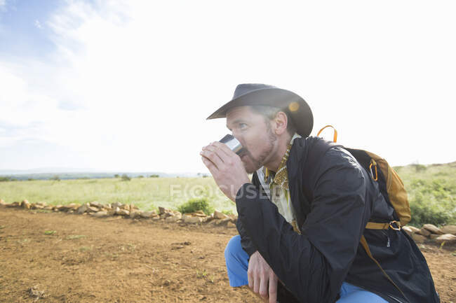 Чоловік п'є з чашки під час походів — стокове фото