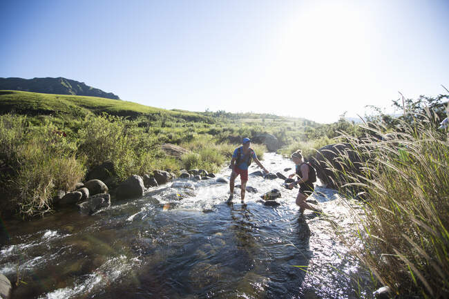 Couple crossing river during hike — Stock Photo