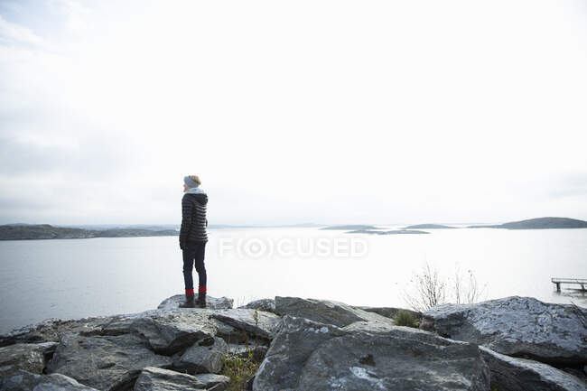 Девушка, стоящая на скале у моря — стоковое фото