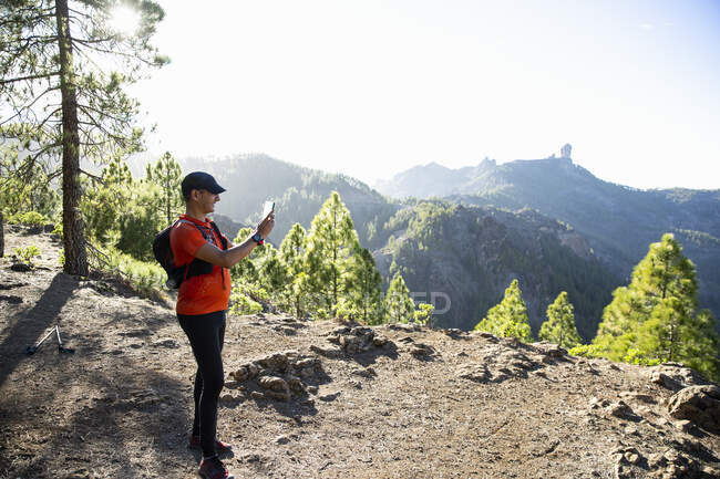 Homem fotografando com telefone inteligente na montanha — Fotografia de Stock